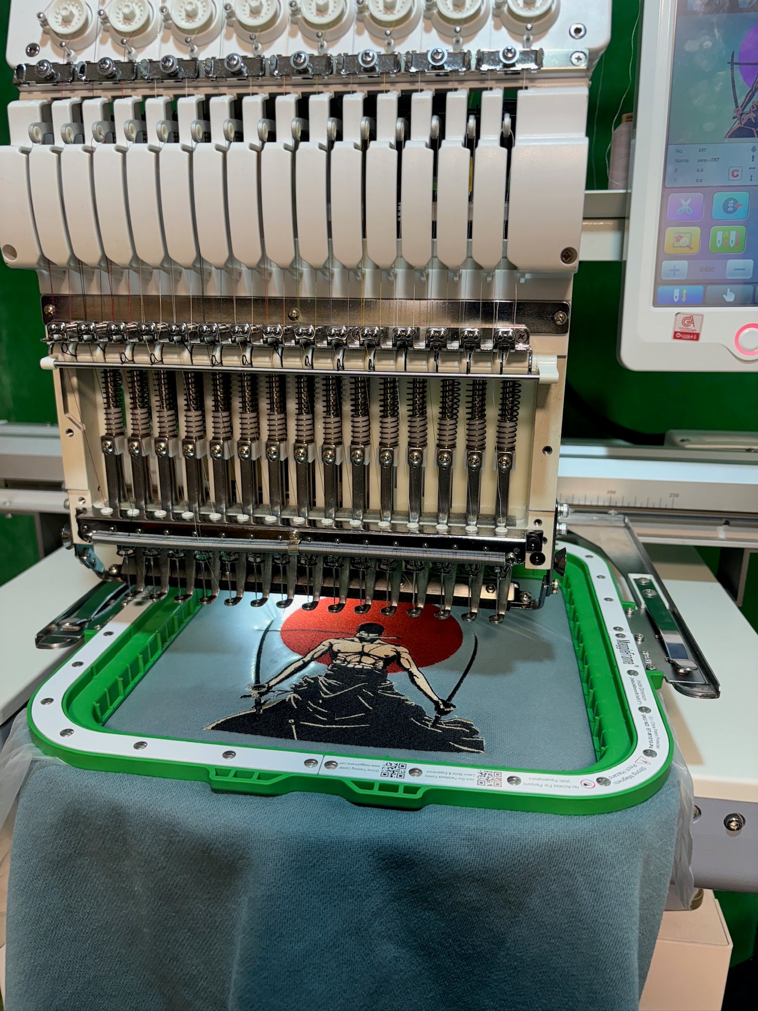 machine a brodé qui brode un pull bleu avec zoro de one piece au milieu